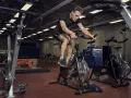 Mężczyzna intensywnie pedałuje na rowerze stacjonarnym, wykonując trening anaerobowy.