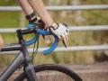 Rowerzysta w rękawiczkach trzyma kierownicę, zbliżając się do swojego progu mleczanowego.