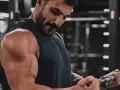 Mężczyzna ćwiczy biceps na siłowni. Zastanawia się nad cytrulina skutki uboczne, ale skupia się na treningu.