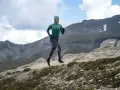 Kobieta w sportowym hidżabie biegnie po górskim szlaku, doskonaląc swoją kadencję w bieganiu.