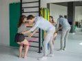 Fizjoterapeuta pomaga kobiecie w ćwiczeniach na kolana z użyciem taśmy oporowej.