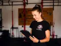 Sylwia, trenerka personalna, przegląda plan treningowy dla kobiet na tablecie w siłowni.