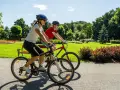 Dwie osoby na rowerach cieszą się pięknym dniem w parku. To pokazuje, co daje jazda na rowerze: radość, aktywność i kontakt z naturą.