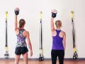 Dwie kobiety wykonują ćwiczenia z kettlebell, aby wzmocnić mięśnie i zapobiec bólowi barku.