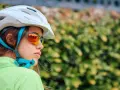 Młoda rowerzystka w kasku i okularach przeciwsłonecznych. Czy kask na rower jest obowiązkowy? Bezpieczeństwo przede wszystkim!