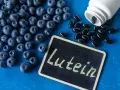 Borówki i kapsułki suplementu diety. Na tabliczce napis "Lutein". Luteina na co? Na zdrowie oczu!