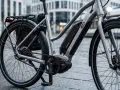 Nowy, srebrny rower elektryczny z bagażnikiem i sakwą, gotowy na miejskie wyzwania. Jaki rower elektryczny wybrać? Ten wygląda świetnie!