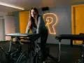 Uśmiechnięta kobieta na rowerze stacjonarnym, gotowa na intensywny trening cardio.
