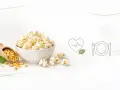 Misternie przygotowany popcorn w misce, obok ziaren kukurydzy na drewnianej łyżce. Czy popcorn tuczy? Ikony serca i talerza sugerują zdrowy wybór.