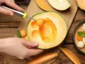 Ręka z gałkownicą wydobywa kulki z melona, ukazując jego soczyste wnętrze. Melon właściwości odżywcze czynią go idealnym na letnie orzeźwienie.