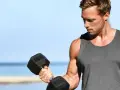 Mężczyzna ćwiczy biceps z hantlem. Zastanawia się, ile serii na klatę w tygodniu będzie optymalne dla jego treningu.