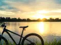 Rower na tle zachodzącego słońca nad jeziorem. Idealne miejsce na odkrywanie tras rowerowych Mazur.