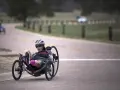 Kobieta w kasku i okularach przeciwsłonecznych na rowerze trójkołowym, intensywny trening HIIT na drodze.