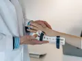 Lekarz zakłada pacjentowi ortezę na nadgarstek, co jest częścią terapii zespołu cieśni nadgarstka ćwiczenia.