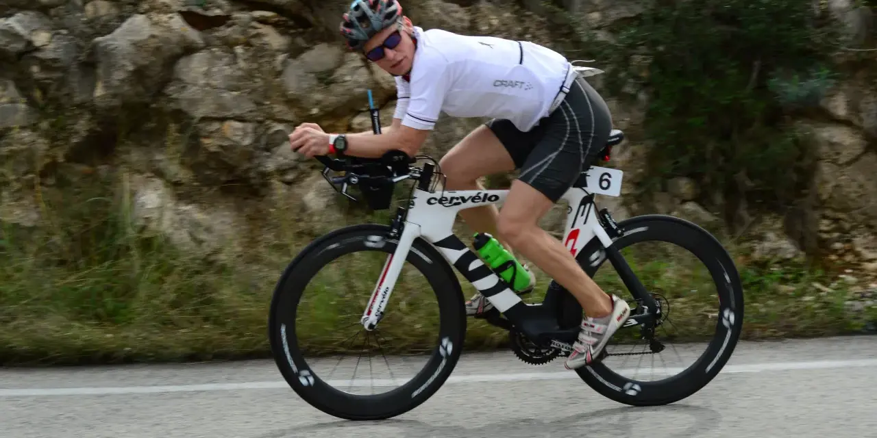 Zawodnik na rowerze triathlonowym pokonuje długi Ironman dystans, pędząc po górskiej trasie.