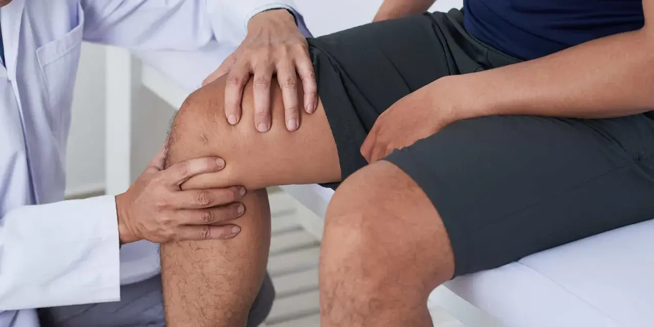 Fizjoterapeuta bada kolano pacjenta, sugerując ćwiczenia na chondromalację rzepki.