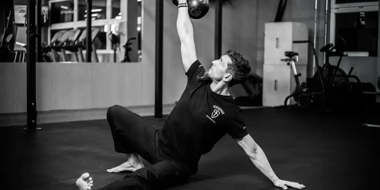 Mężczyzna wykonuje ćwiczenia na siłowni z kettlebell.