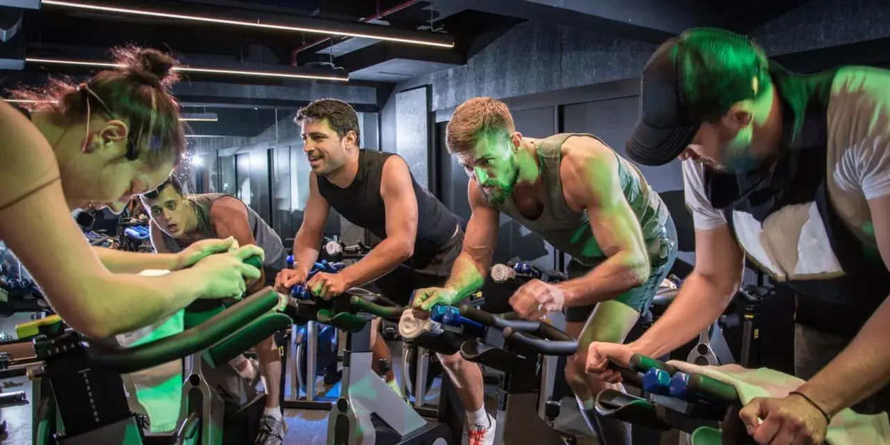 Intensywny trening spinningowy w grupie. Ludzie z determinacją kręcą pedałami, każdy w swoim rytmie.