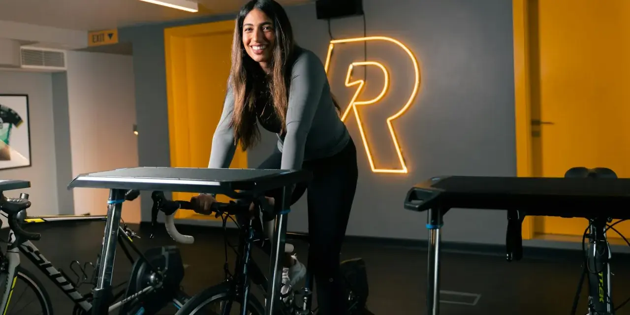 Uśmiechnięta kobieta na rowerze stacjonarnym, gotowa na intensywny trening cardio.