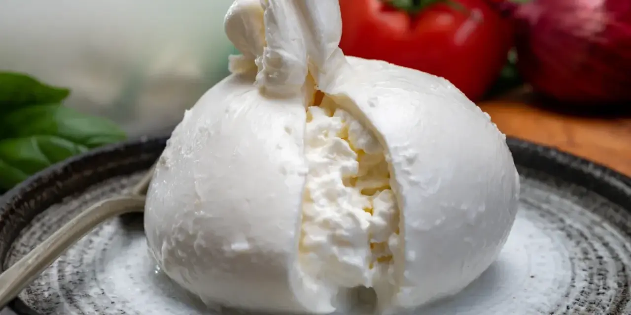 Pyszna burrata na talerzu, z pomidorem i cebulą w tle. Zastanawiasz się nad burrata kcal?