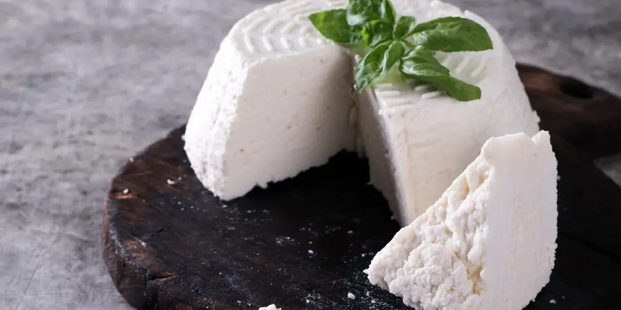 Świeża ricotta z bazylią na ciemnej desce. Idealna do lekkich posiłków, dbając o ricotta kcal.
