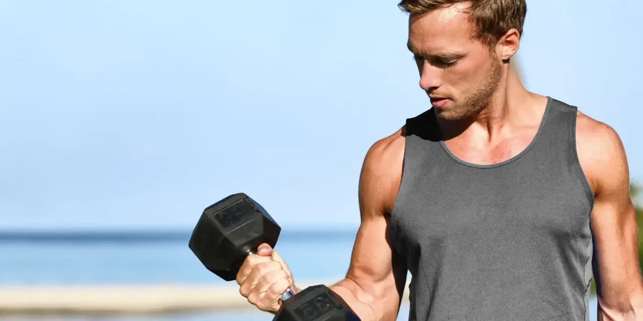 Mężczyzna ćwiczy biceps z hantlem. Zastanawia się, ile serii na klatę w tygodniu będzie optymalne dla jego treningu.