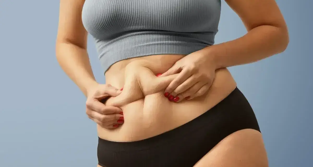 Kobieta z widocznym fałdem tłuszczu na brzuchu, mimo szczupłej sylwetki. Zjawisko "skinny fat" w praktyce.