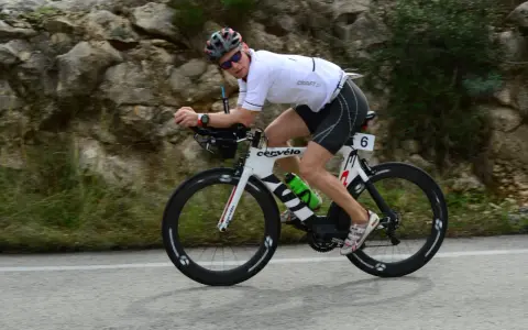 Zawodnik na rowerze triathlonowym pokonuje długi Ironman dystans, pędząc po górskiej trasie.