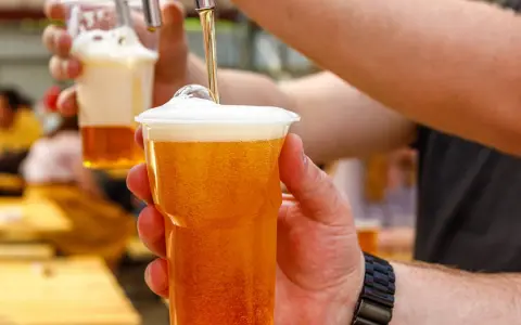 Nalewanie piwa bezalkoholowego do kubka. Zastanawiasz się, ile kalorii ma piwo bezalkoholowe? To świetny wybór na orzeźwienie!