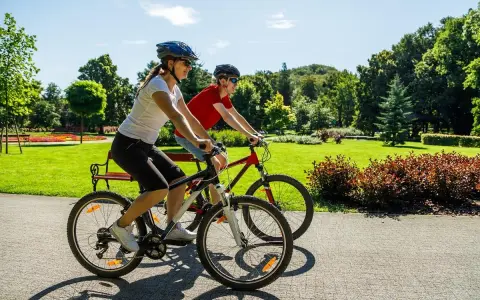 Dwie osoby na rowerach cieszą się pięknym dniem w parku. To pokazuje, co daje jazda na rowerze: radość, aktywność i kontakt z naturą.
