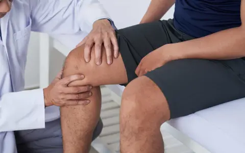 Fizjoterapeuta bada kolano pacjenta, sugerując ćwiczenia na chondromalację rzepki.