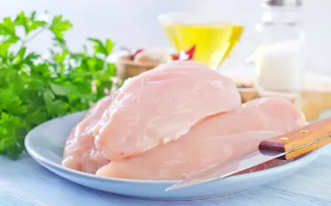 Surowe filety z kurczaka na talerzu, gotowe do przygotowania. W tle olej, sól i natka pietruszki. Idealne dla dbających o filet z kurczaka kcal.