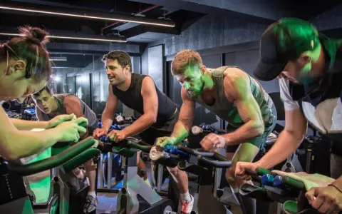 Intensywny trening spinningowy w grupie. Ludzie z determinacją kręcą pedałami, każdy w swoim rytmie.