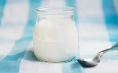 Słoiczek z domowym jogurtem, pełnym naturalnych probiotyków, czeka na łyżeczkę.