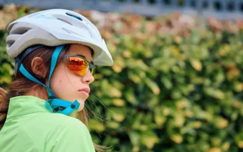 Młoda rowerzystka w kasku i okularach przeciwsłonecznych. Czy kask na rower jest obowiązkowy? Bezpieczeństwo przede wszystkim!