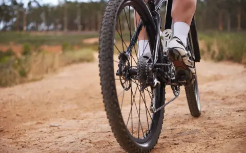Noga rowerzysty na pedale, jazda po piaszczystej ścieżce. Świetny sposób, jak poprawić kondycję.