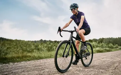 Kobieta na rowerze pokonuje szutrową drogę, wybierając trasę gravel czy cross.