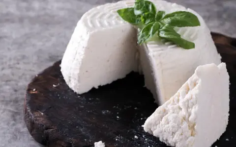 Świeża ricotta z bazylią na ciemnej desce. Idealna do lekkich posiłków, dbając o ricotta kcal.