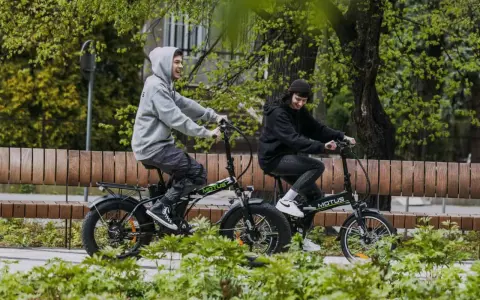 Dwaj młodzi ludzie cieszą się jazdą na rowerach elektrycznych. Dofinansowanie do roweru elektrycznego sprawia, że ekologiczny transport jest dostępny dla każdego.