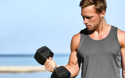 Mężczyzna ćwiczy biceps z hantlem. Zastanawia się, ile serii na klatę w tygodniu będzie optymalne dla jego treningu.