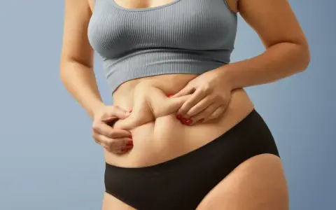 Kobieta z widocznym fałdem tłuszczu na brzuchu, mimo szczupłej sylwetki. Zjawisko "skinny fat" w praktyce.