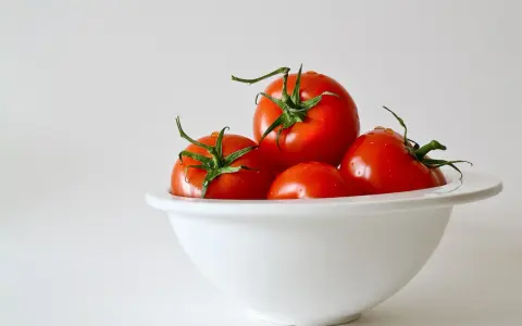 Kilka soczystych pomidorów w białej misce. Niska zawartość pomidor kcal sprawia, że są idealne na zdrową przekąskę.