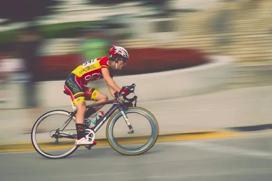 Kolarz w żółto-czerwonym stroju pędzi na rowerze, pokonując kolejne kilometry ultramaratonu.