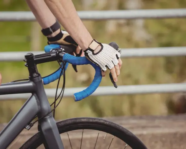 Rowerzysta w rękawiczkach trzyma kierownicę, zbliżając się do swojego progu mleczanowego.