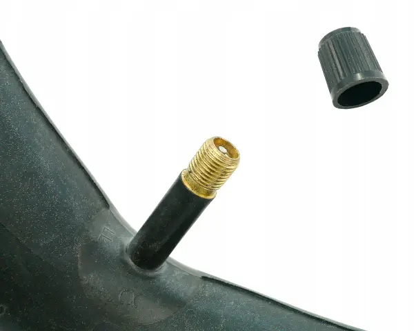 Złoty wentyl schrader na czarnej dętce rowerowej, obok leży czarna nakrętka.
