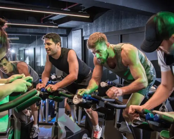 Intensywny trening spinningowy w grupie. Ludzie z determinacją kręcą pedałami, każdy w swoim rytmie.