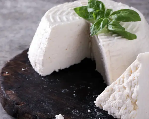 Świeża ricotta z bazylią na ciemnej desce. Idealna do lekkich posiłków, dbając o ricotta kcal.