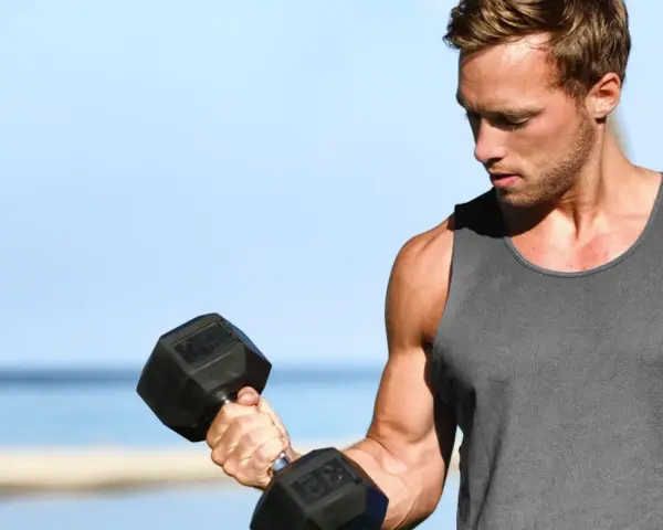Mężczyzna ćwiczy biceps z hantlem. Zastanawia się, ile serii na klatę w tygodniu będzie optymalne dla jego treningu.