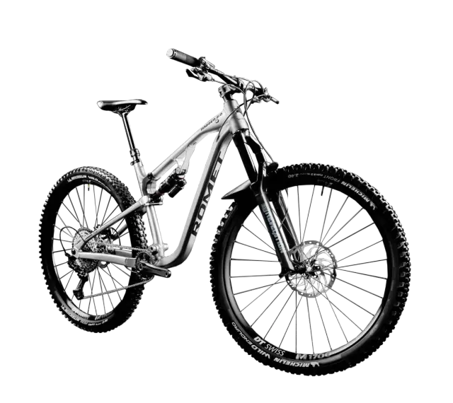 Srebrny rower MTB Romet Dagger 2.0 z pełnym zawieszeniem i oponami Michelin Wild Enduro. To sprzęt do pokonywania trudnych tras.