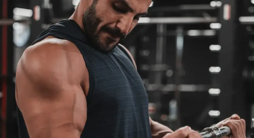 Mężczyzna ćwiczy biceps na siłowni. Zastanawia się nad cytrulina skutki uboczne, ale skupia się na treningu.